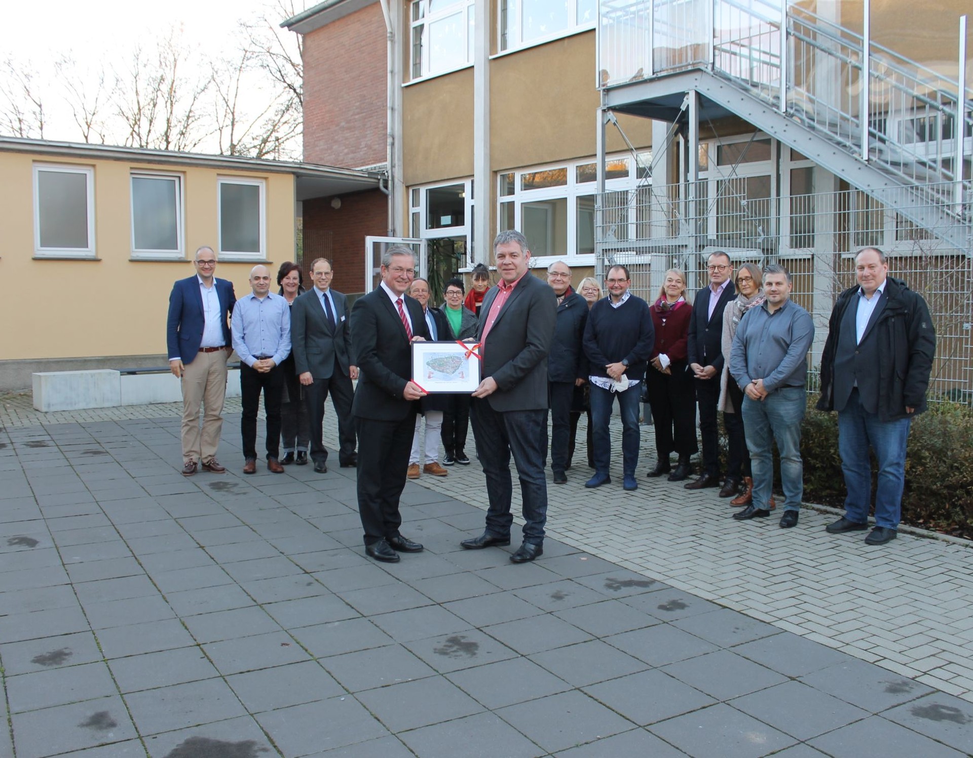 Bürgermeister Michael Dreier überreicht für die neuen Räume Schulleiter Christian Bohle ein Bild des bekannten Paderborner Künstlers Herman Reichold.